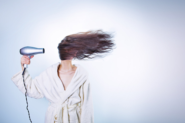 Woman blow drying long brown hair
