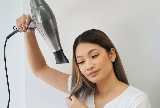 woman blow drying hair using a vs sassoon 3Q brushless digital hair dryer