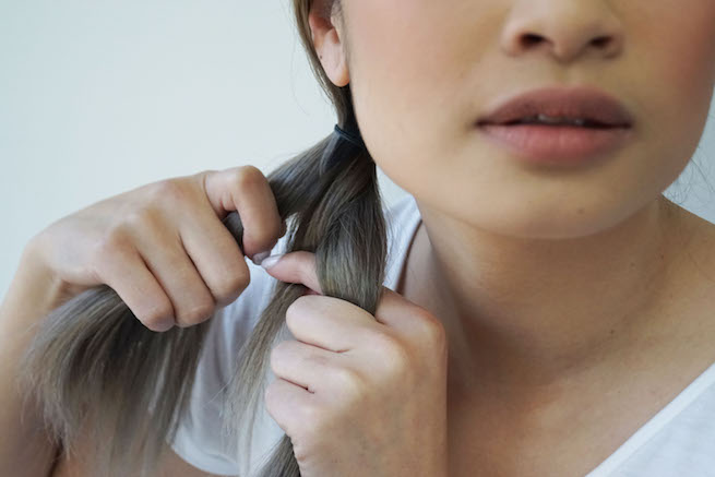 Woman demonstrating how to wrap your hair into a fishtail braid style