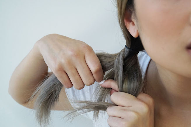woman wrapping hair sections into fishtail braid