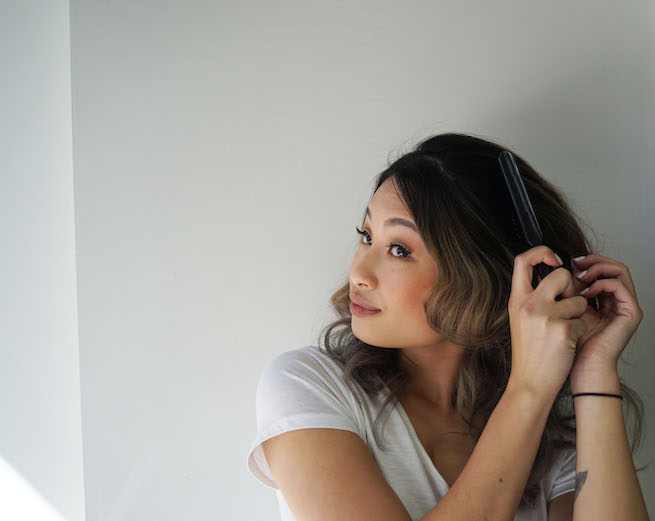 woman brushing out curled hair