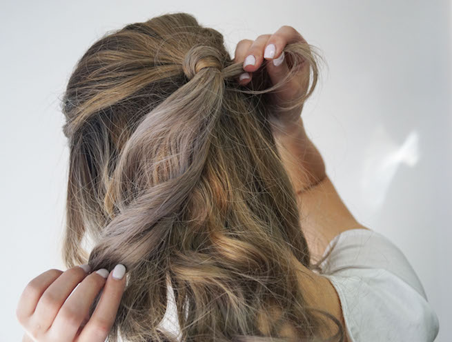 woman demonstrating how to cover hair ties and bobby pins using pony tail and a section of hair