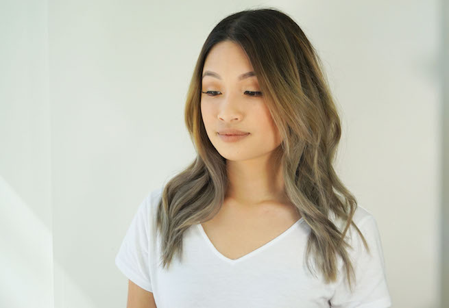 woman with curled hair about to demonstrate side swept braid hairstyle