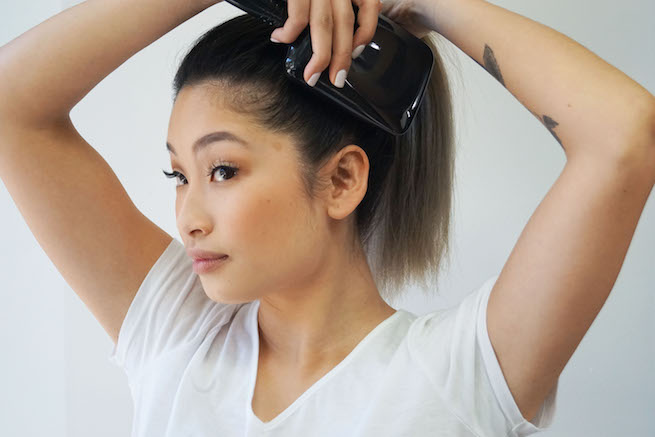 woman brushing hair for sleek ponytail hairstyle