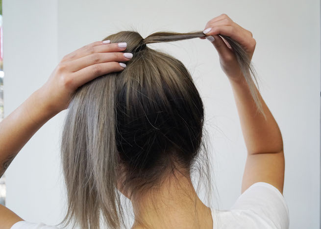 Woman concealing hair tie using section of hair for a sleek pony tail hairstyle