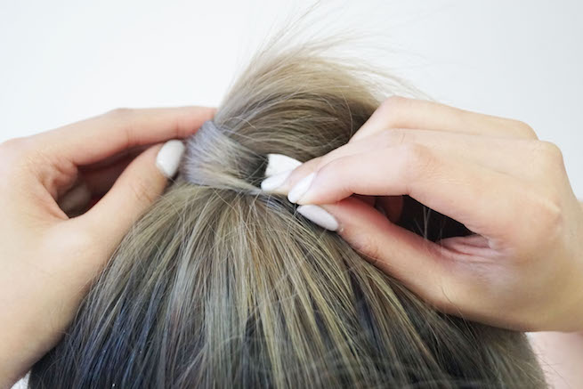 Close up shot of hair used to conceal hair tie for a sleek pony tail style